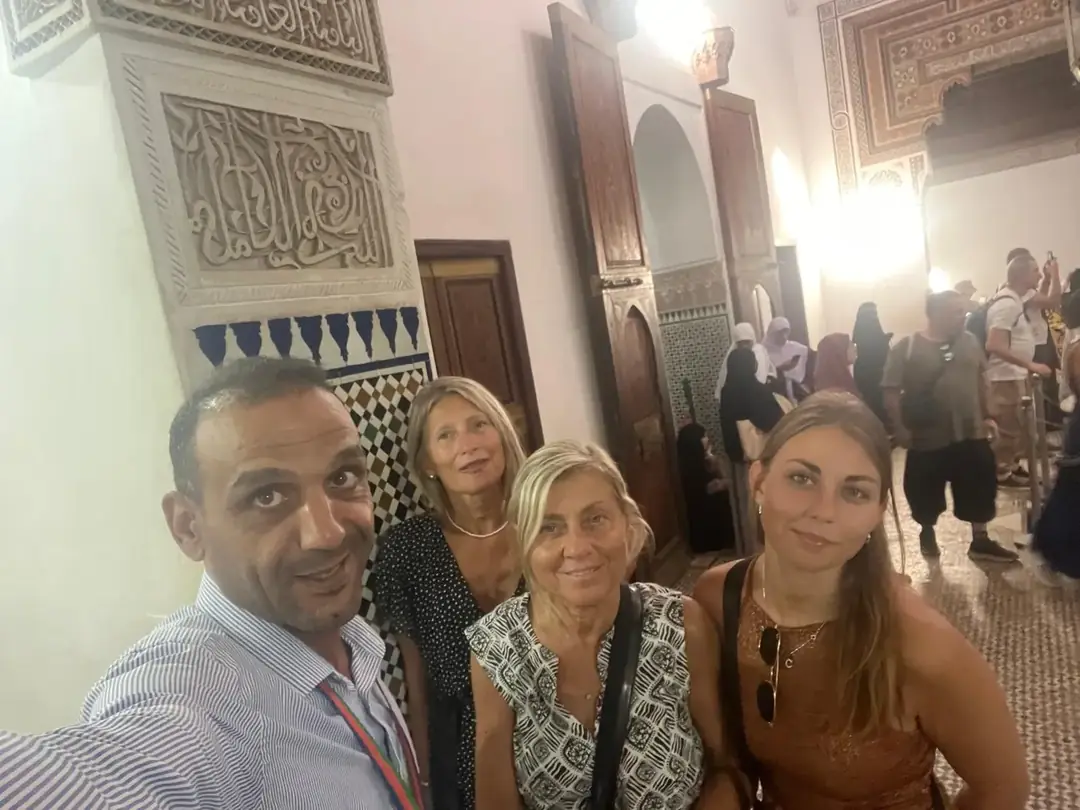Youssef taking a selfie with three travellers in an ornate carved-plaster hall