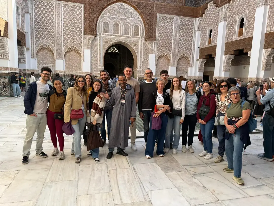 Youssef with a large group of travellers in a carved marble courtyard in Marrakech